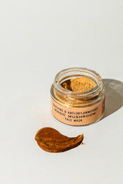 A small open jar labeled TESTER — Magic Mushroom Face Mask from Good Flower Farm sits on a white surface, with a smear of the nourishing mushroom skincare mask spread beside it.