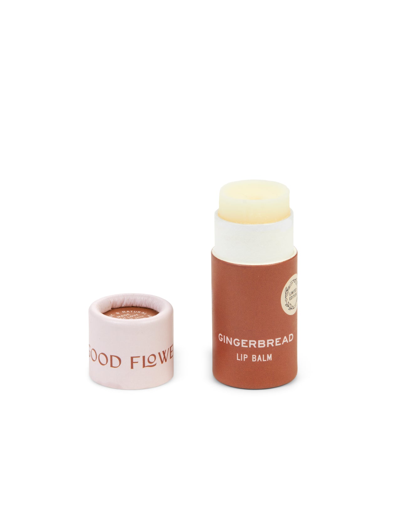 A tube from the SEASONAL LIMITED Holiday Lip Gift Set - NEW by Good Flower Farm with its biodegradable cap showing GOOD FLOWER, brown tube with white text, and light cream coconut oil-infused balm. Cap is removed and placed beside the tube.