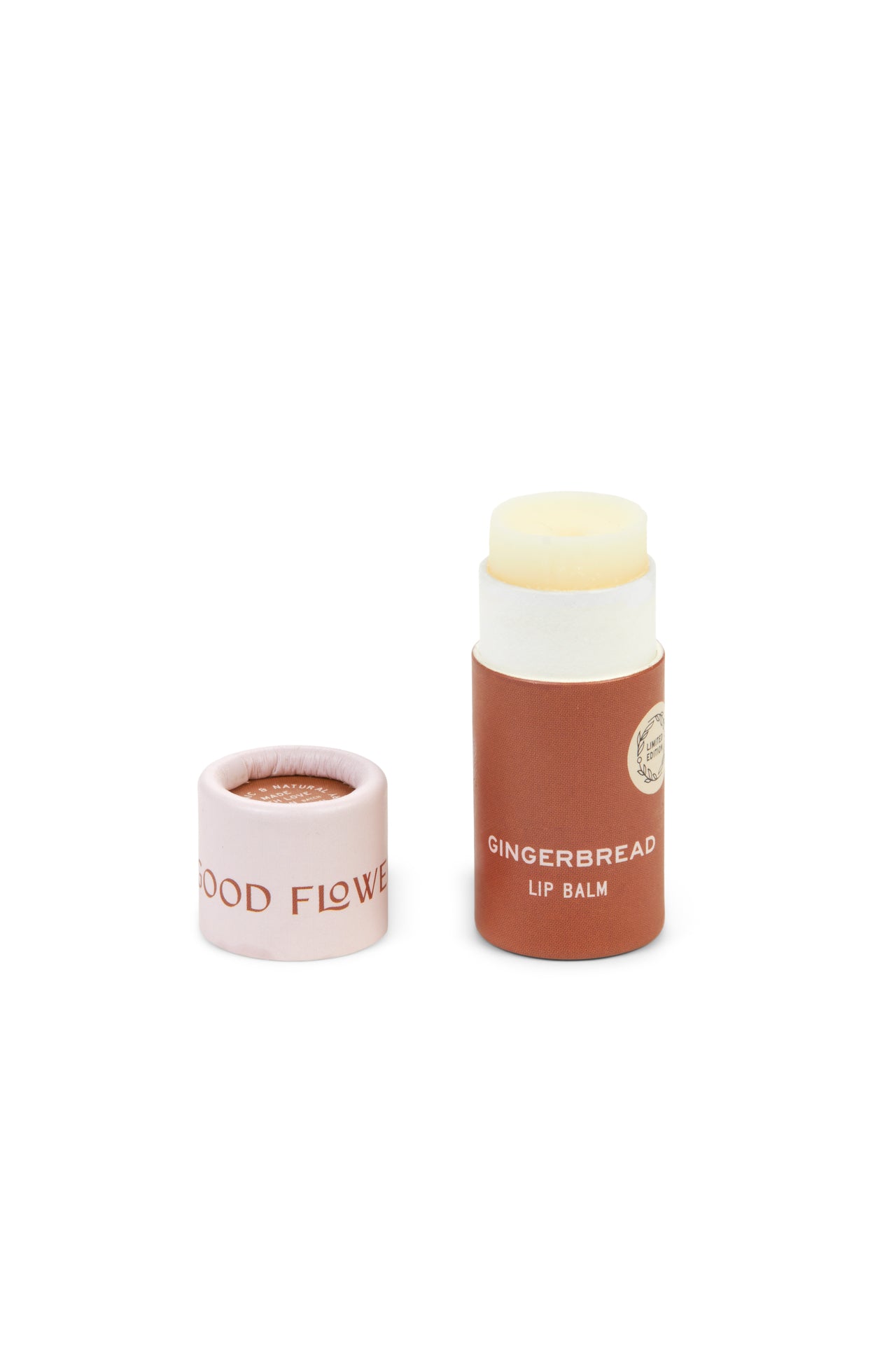 A tube from the SEASONAL LIMITED Holiday Lip Gift Set - NEW by Good Flower Farm with its biodegradable cap showing GOOD FLOWER, brown tube with white text, and light cream coconut oil-infused balm. Cap is removed and placed beside the tube.