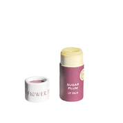 A SEASONAL LIMITED Holiday Lip Gift Set - NEW lip balm by Good Flower Farm with a purple label and biodegradable tube stands next to its white cap on a white background. The coconut oil balm is partially exposed above the tube.